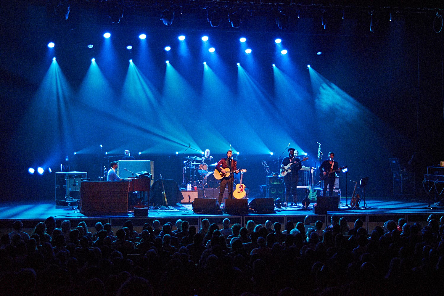 Band performing live on stage with blue lighting.