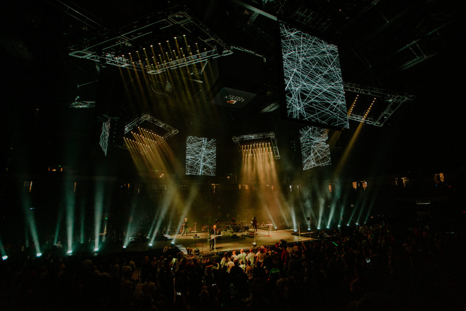 A concert stage illuminated with dramatic lighting and large screens.