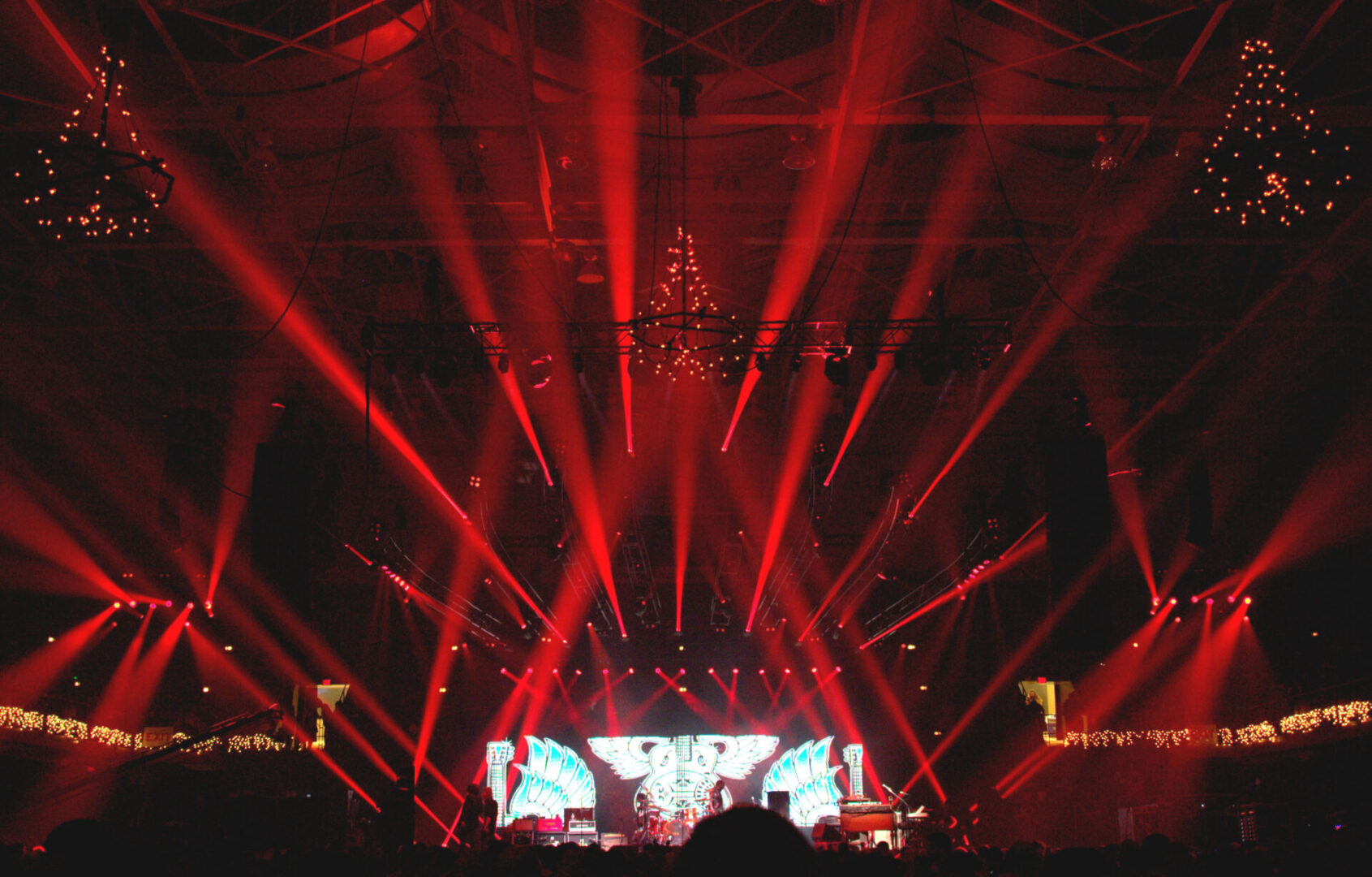 Dynamic red laser light show illuminating a dark stage with a crowd.