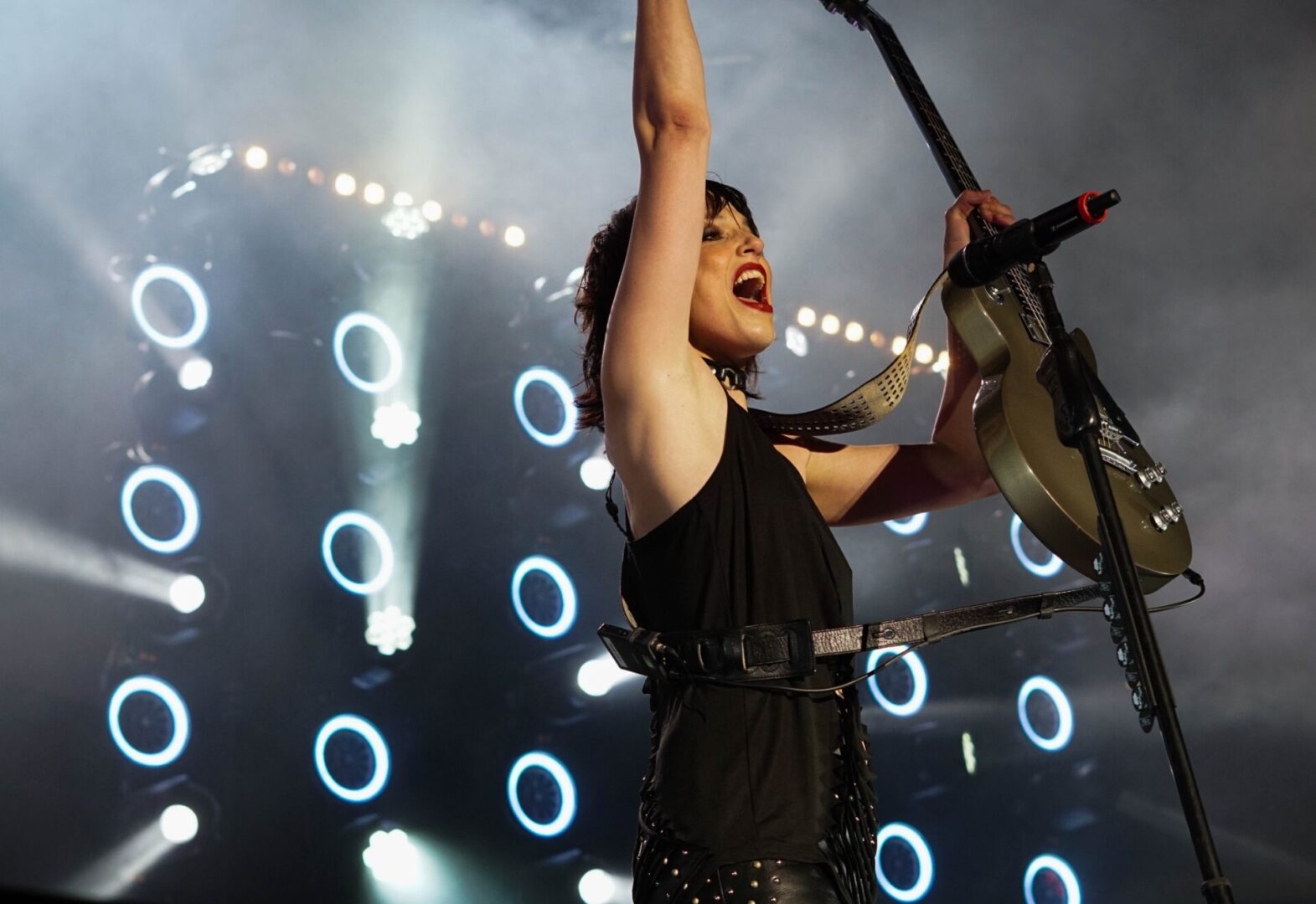 Energetic musician passionately singing on stage with dynamic lighting.