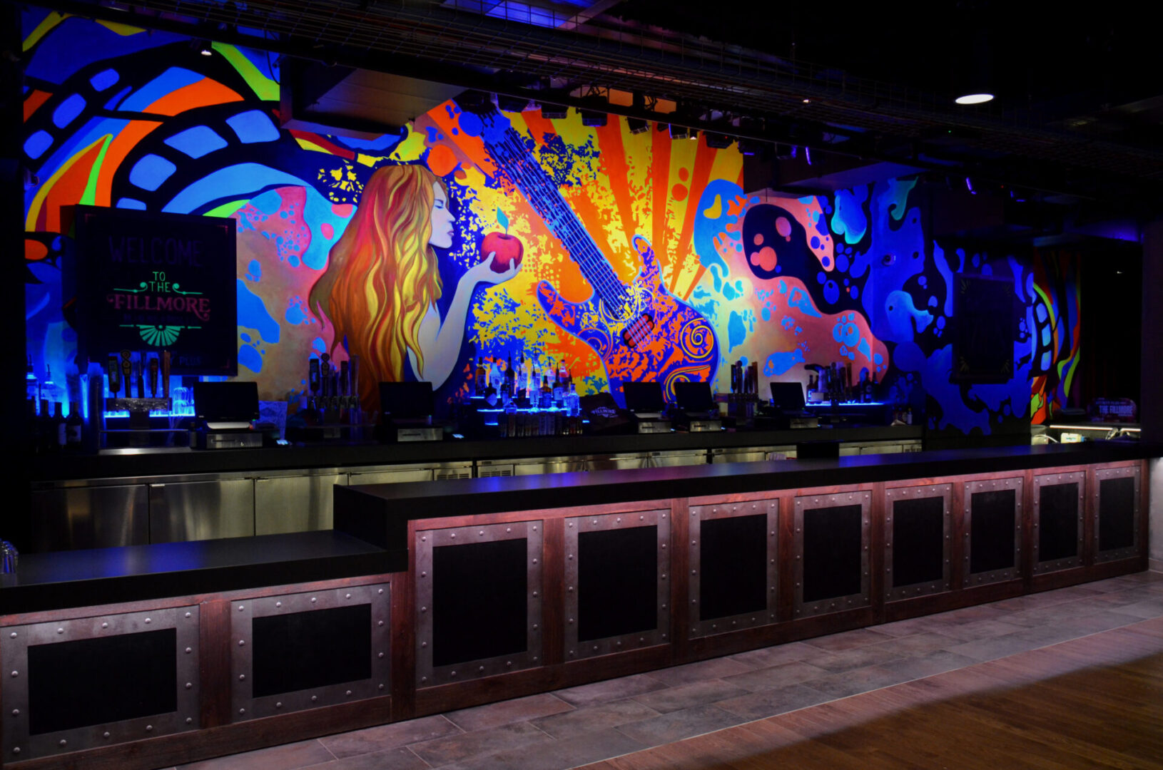 Vibrant mural with animals and colorful patterns in a dimly lit room.