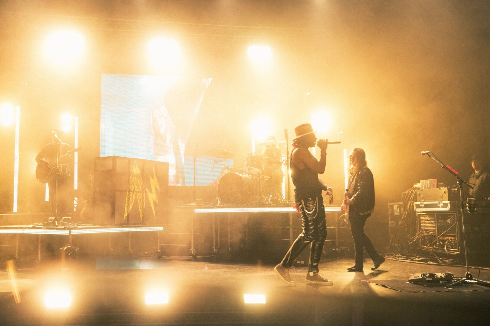 Two people performing on a brightly lit stage with warm lighting.