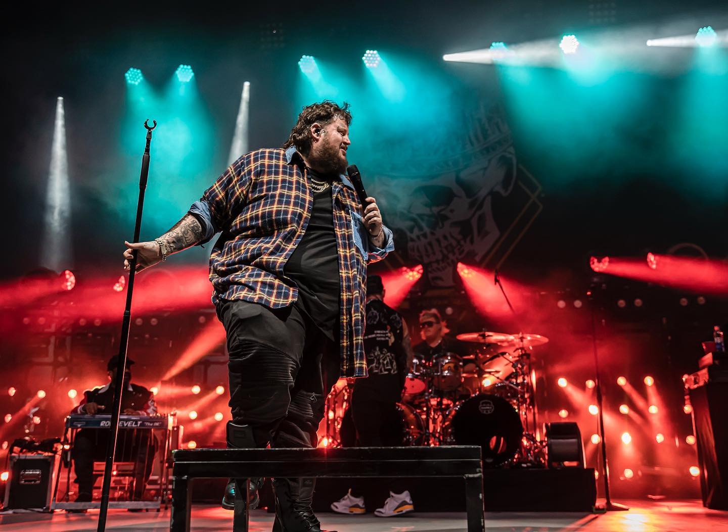 A performer passionately singing on stage with vibrant lighting.