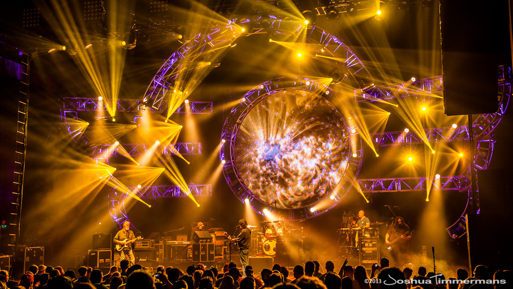 Concert stage with vibrant golden lights and a large circular display.