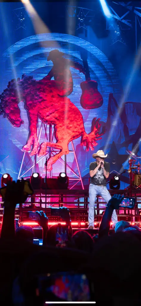 Country singer performing live on stage with colorful lighting.