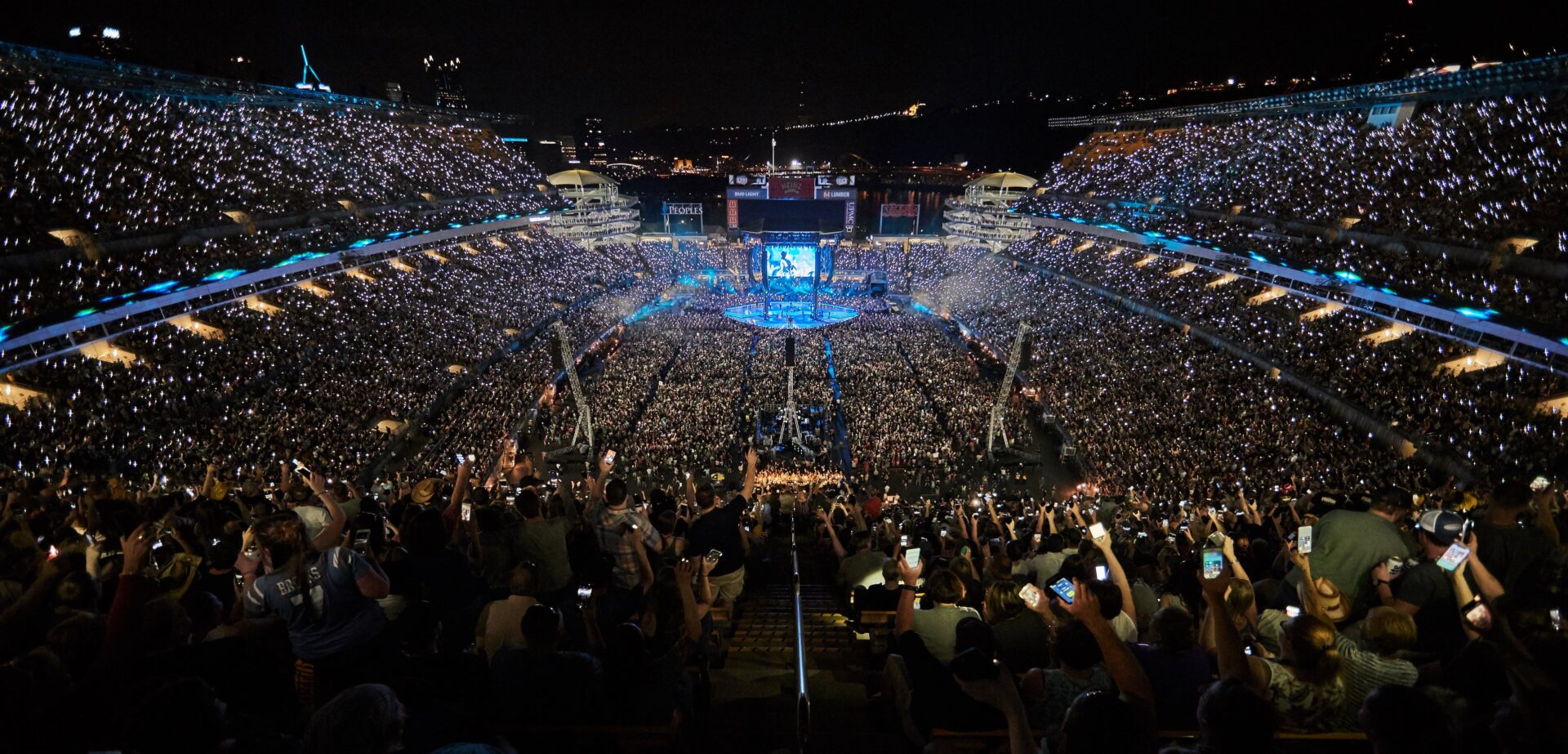 A packed stadium during a nighttime event with bright stage lights.