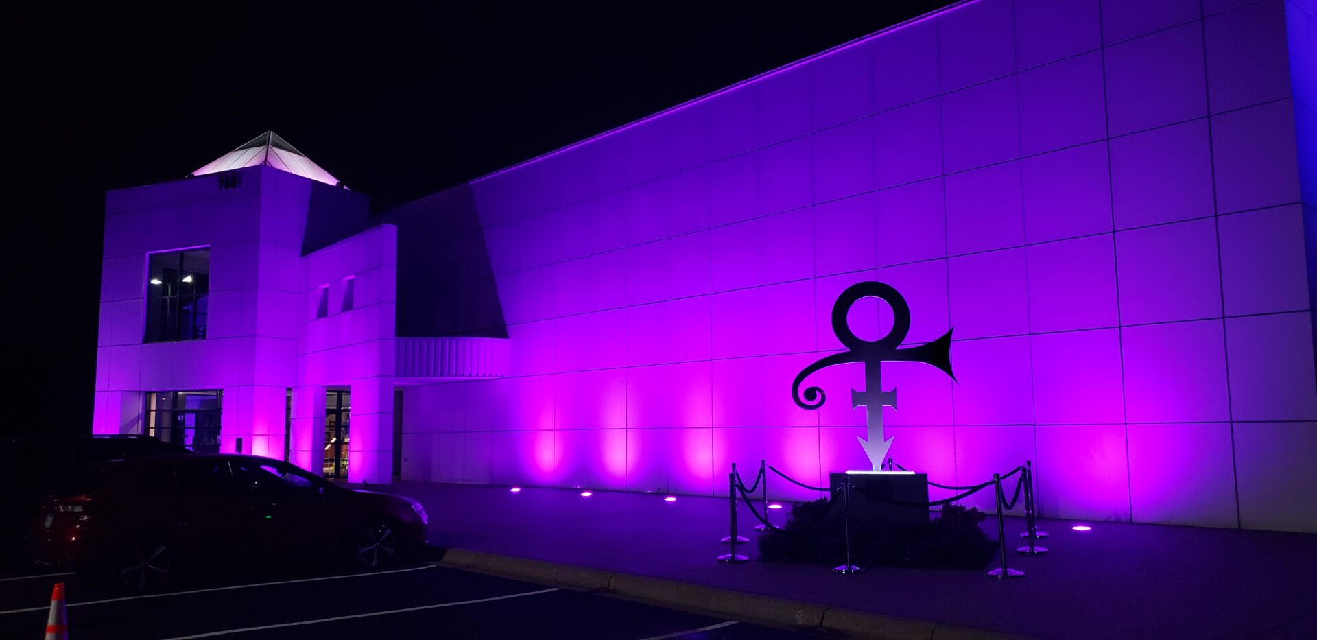 Building illuminated in purple with a large symbol statue.