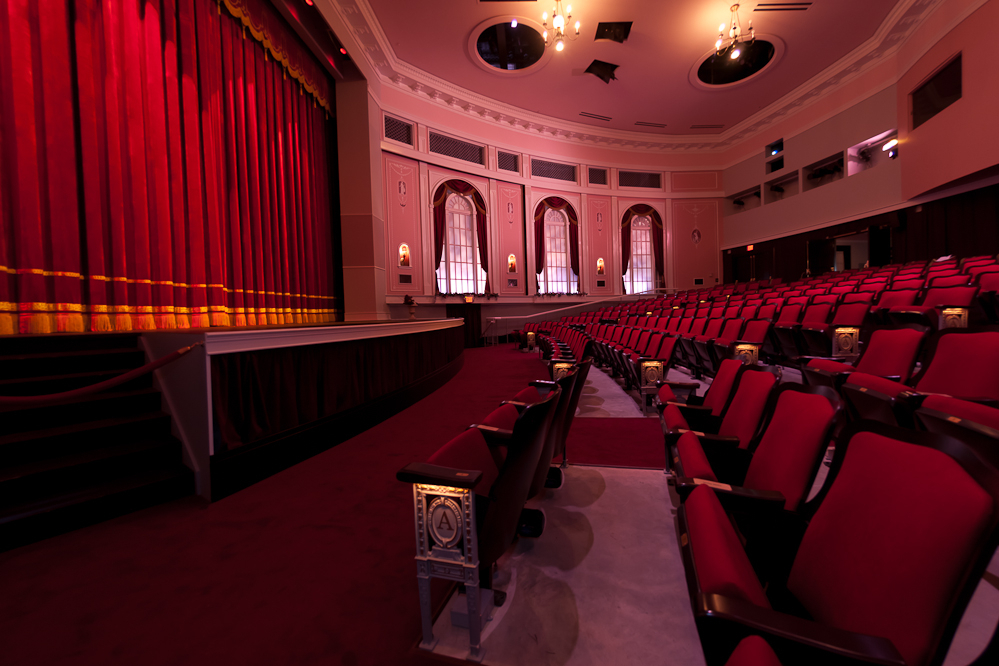 Empty theater with red seats and stage curtain.