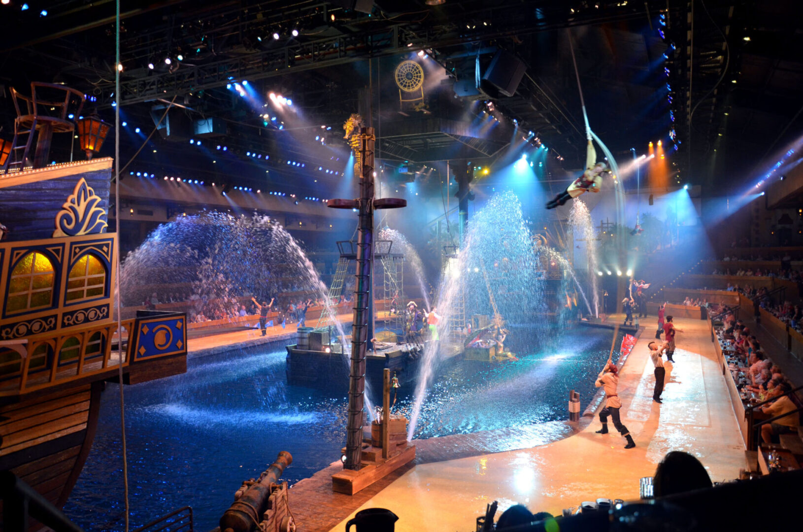 A lively water-themed stage show with performers and water sprays in an arena.