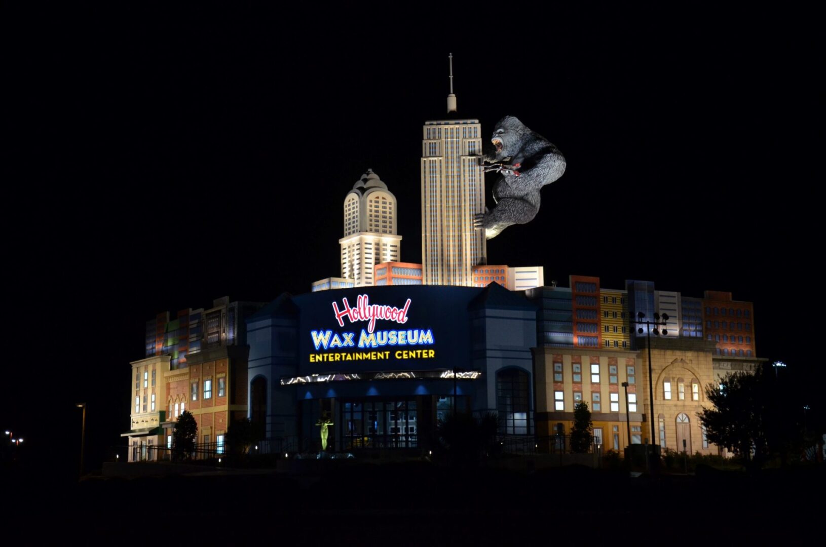 Skateboarder performing a trick at night in front of a lit-up building.