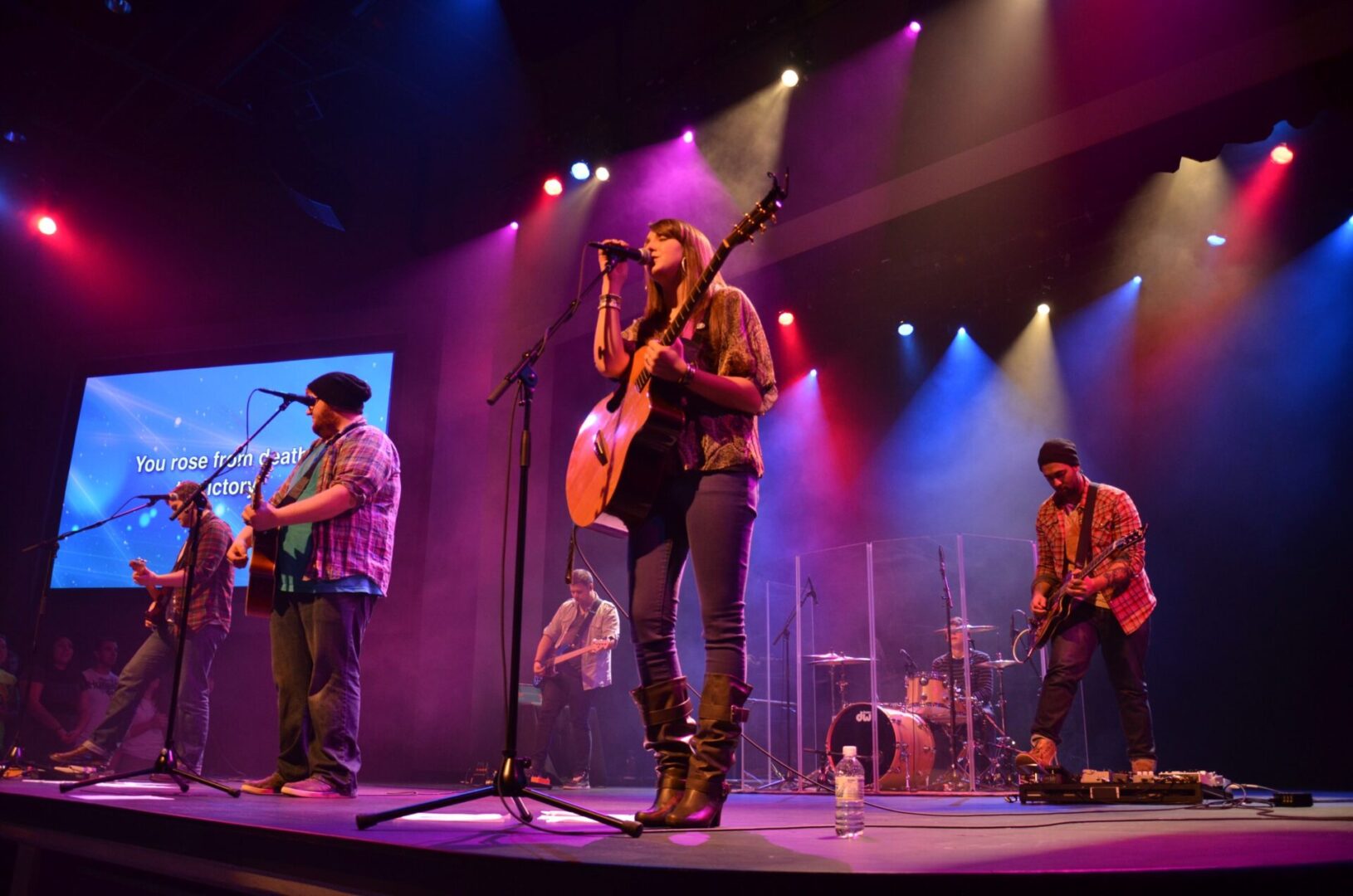 Band performing live on stage with colorful lights.