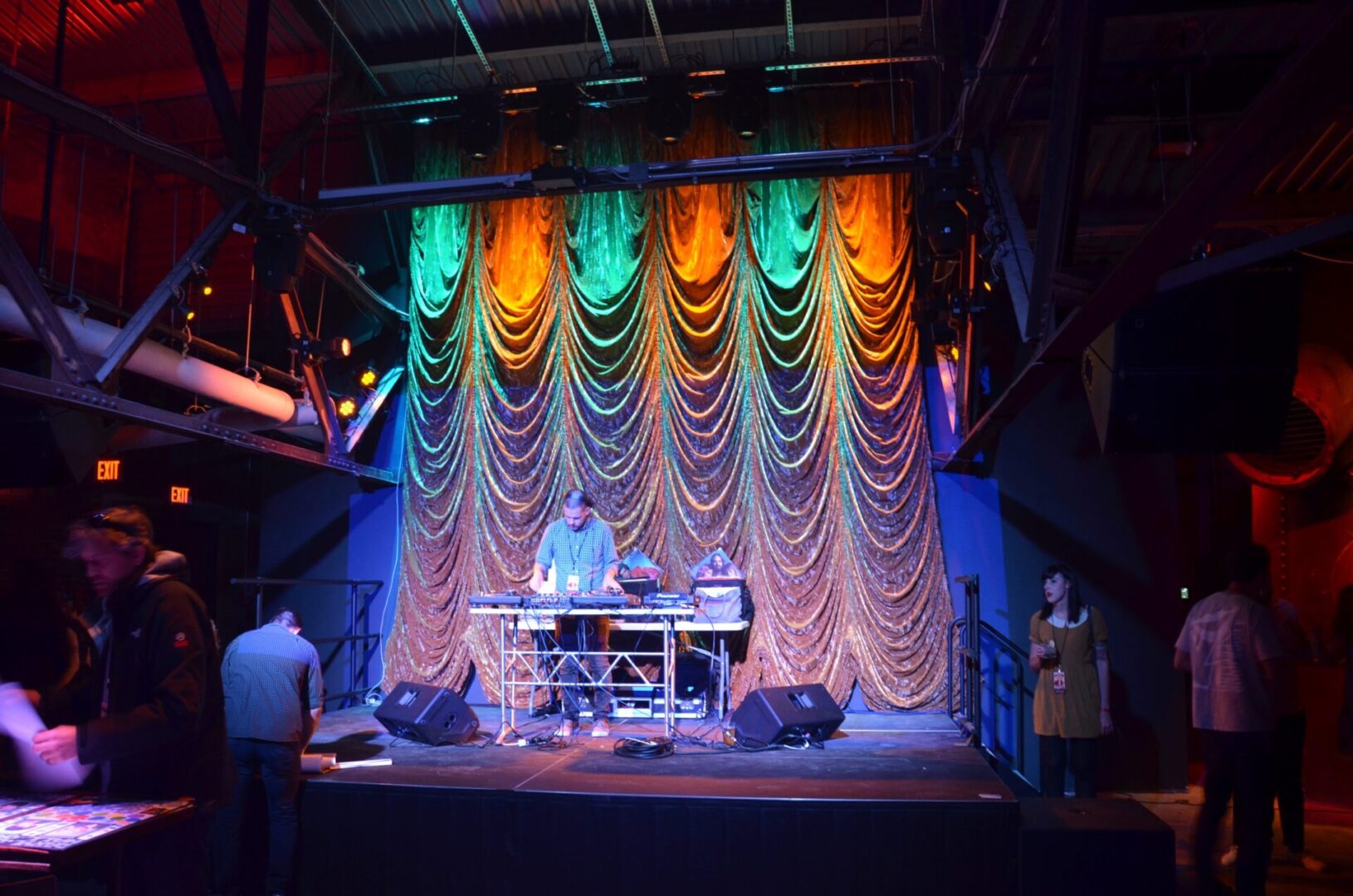 Musicians performing on stage with colorful lights and a curtain backdrop.