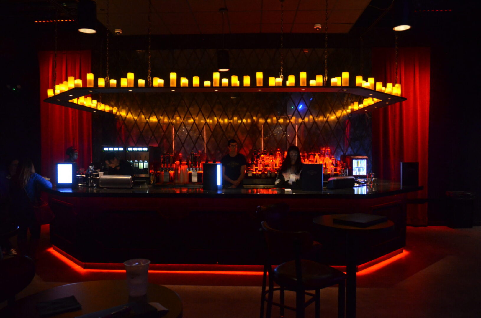 Cozy bar interior with warm candlelight and stage setup.