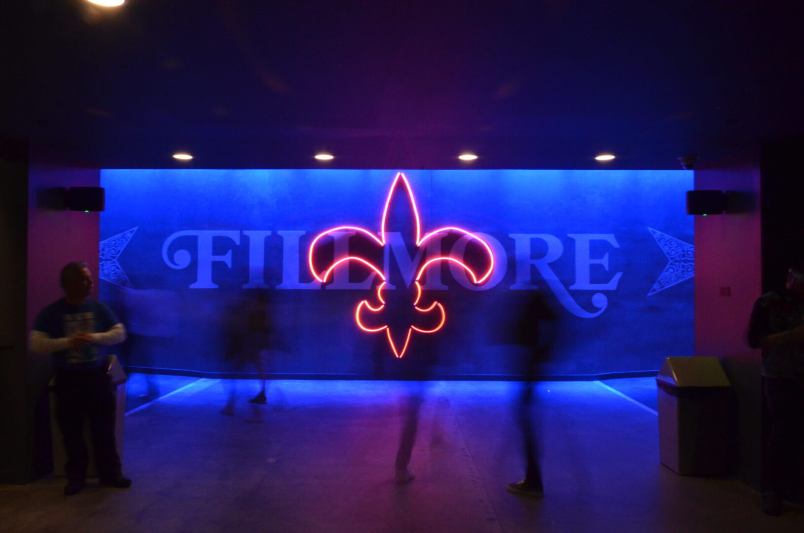 Neon pink fleur-de-lis symbol glowing against a blue backdrop.