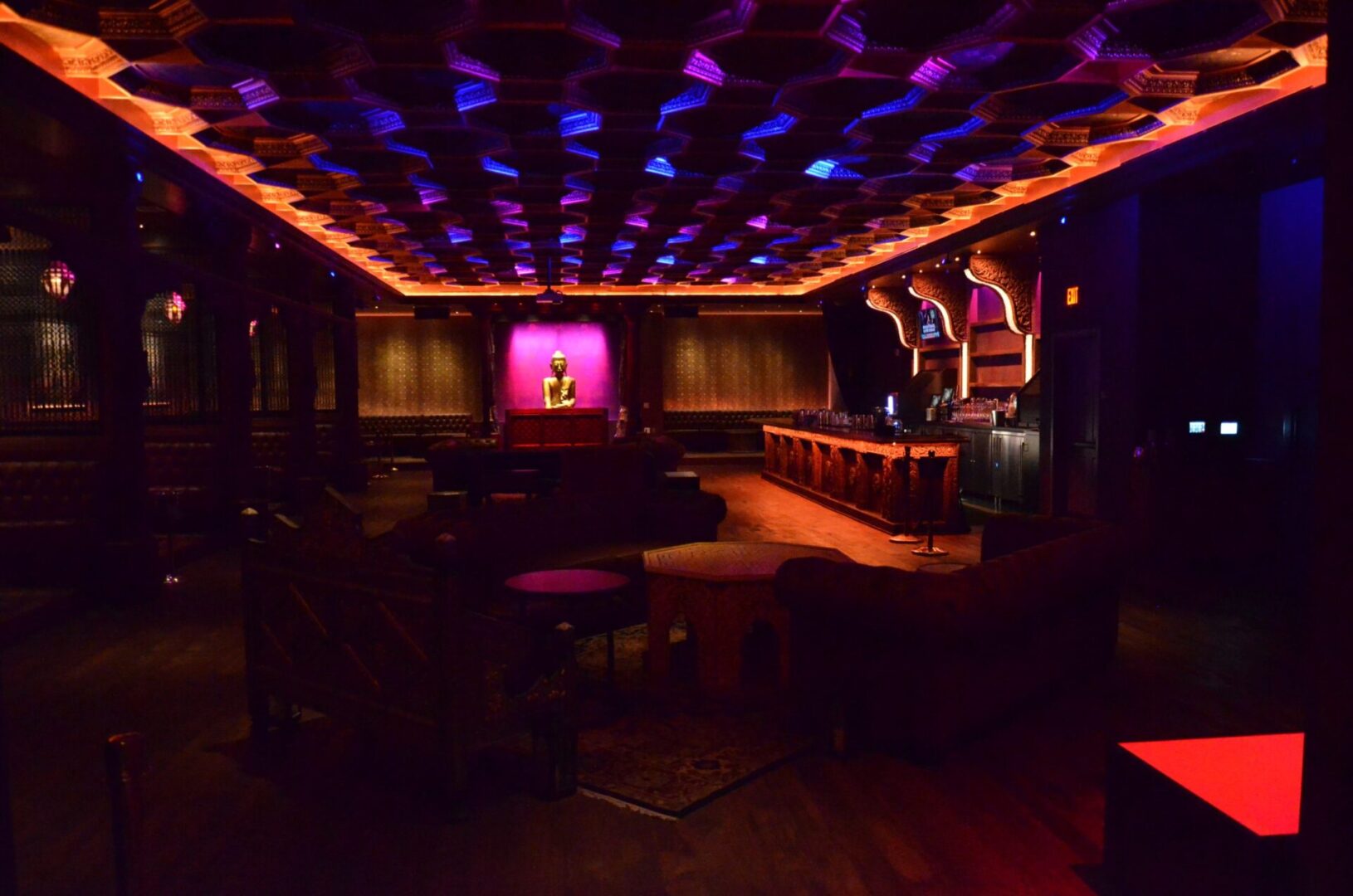 Dimly lit lounge with colorful ceiling lights and cozy seating.