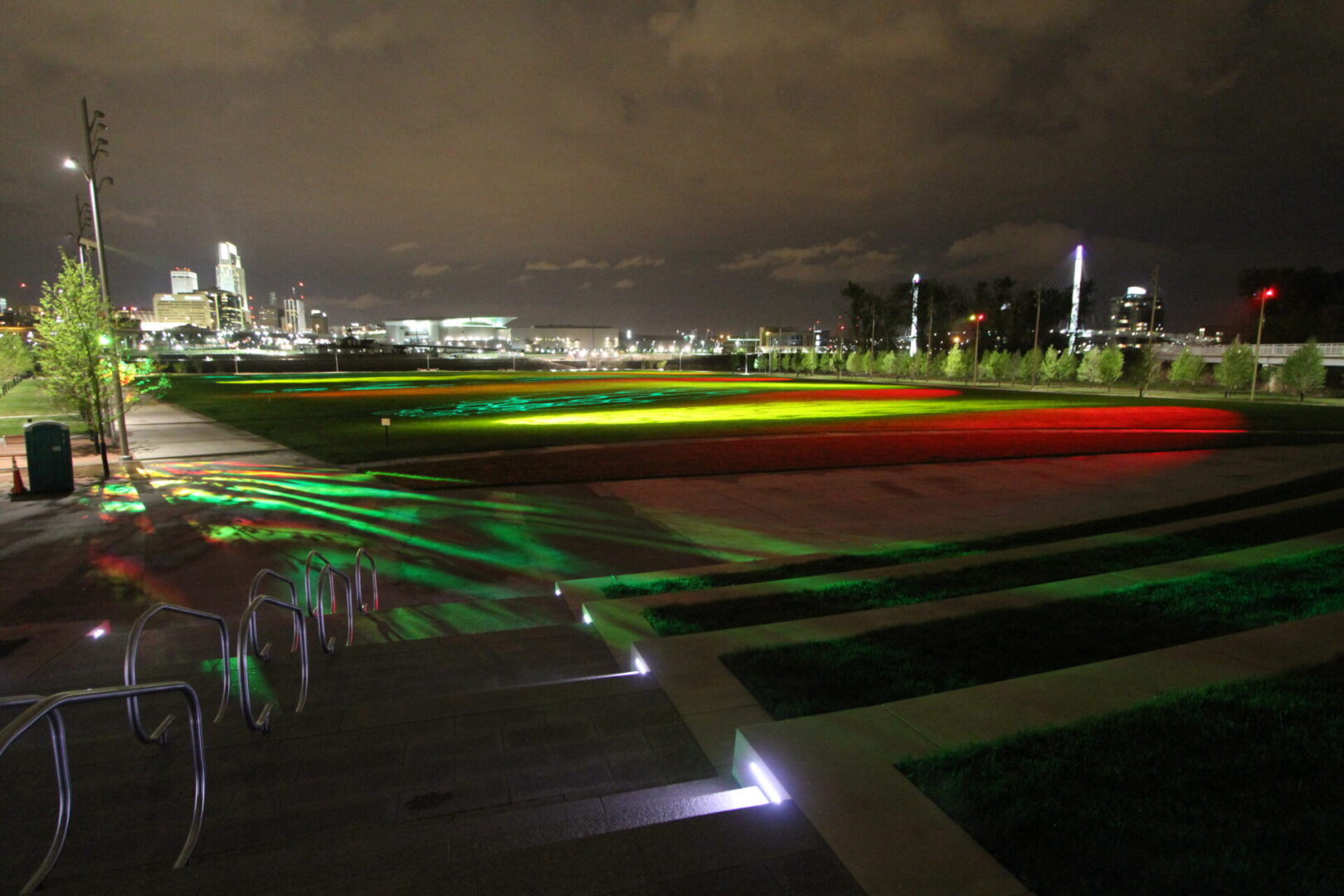 City skyline at night with colorful light trails on a large open field.