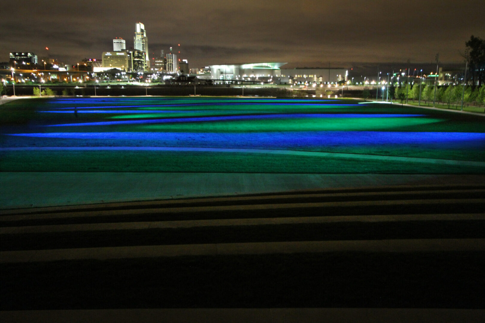 City skyline at night with colorful light trails over water.