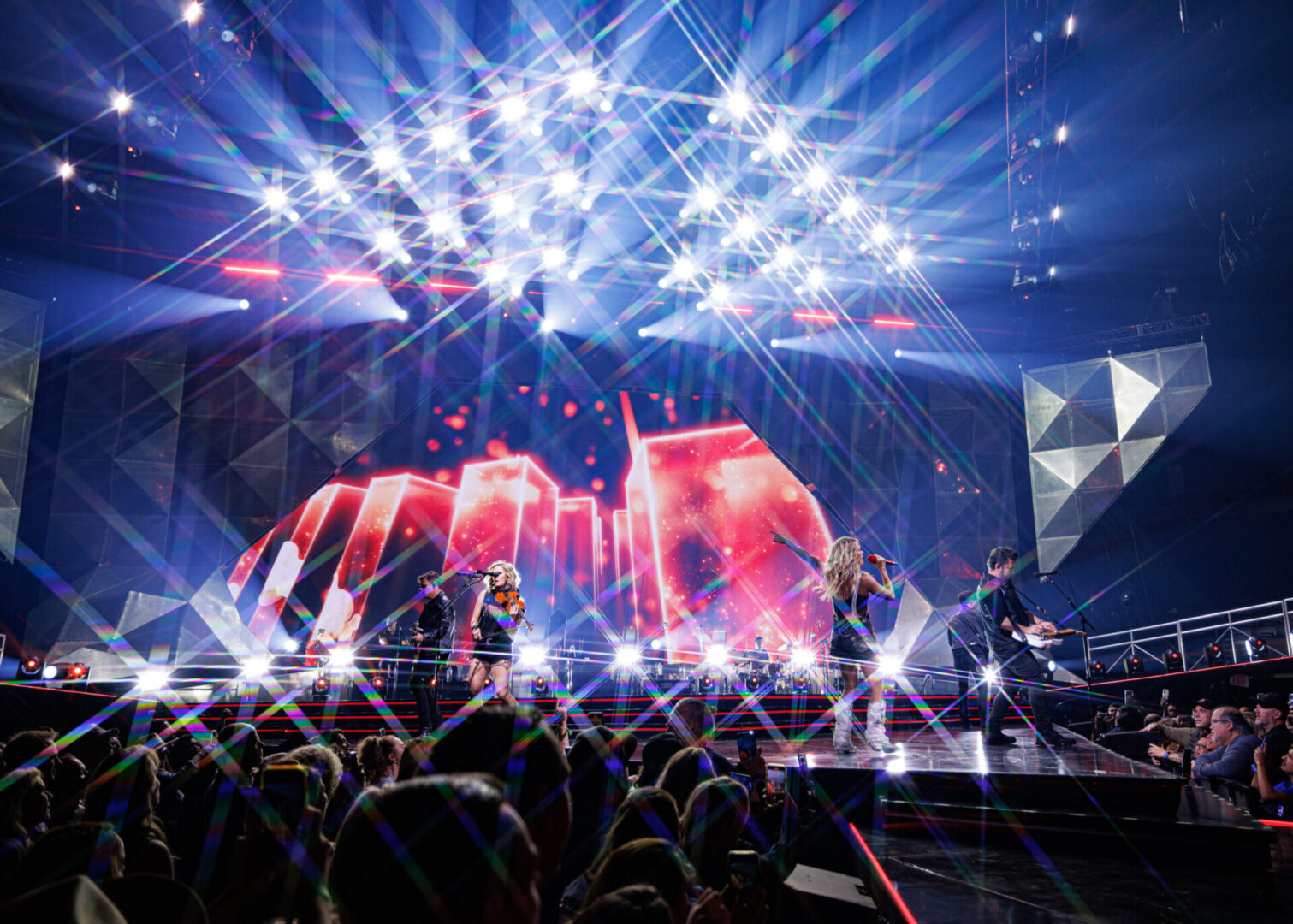Energetic concert scene with vibrant lights and a cheering crowd.