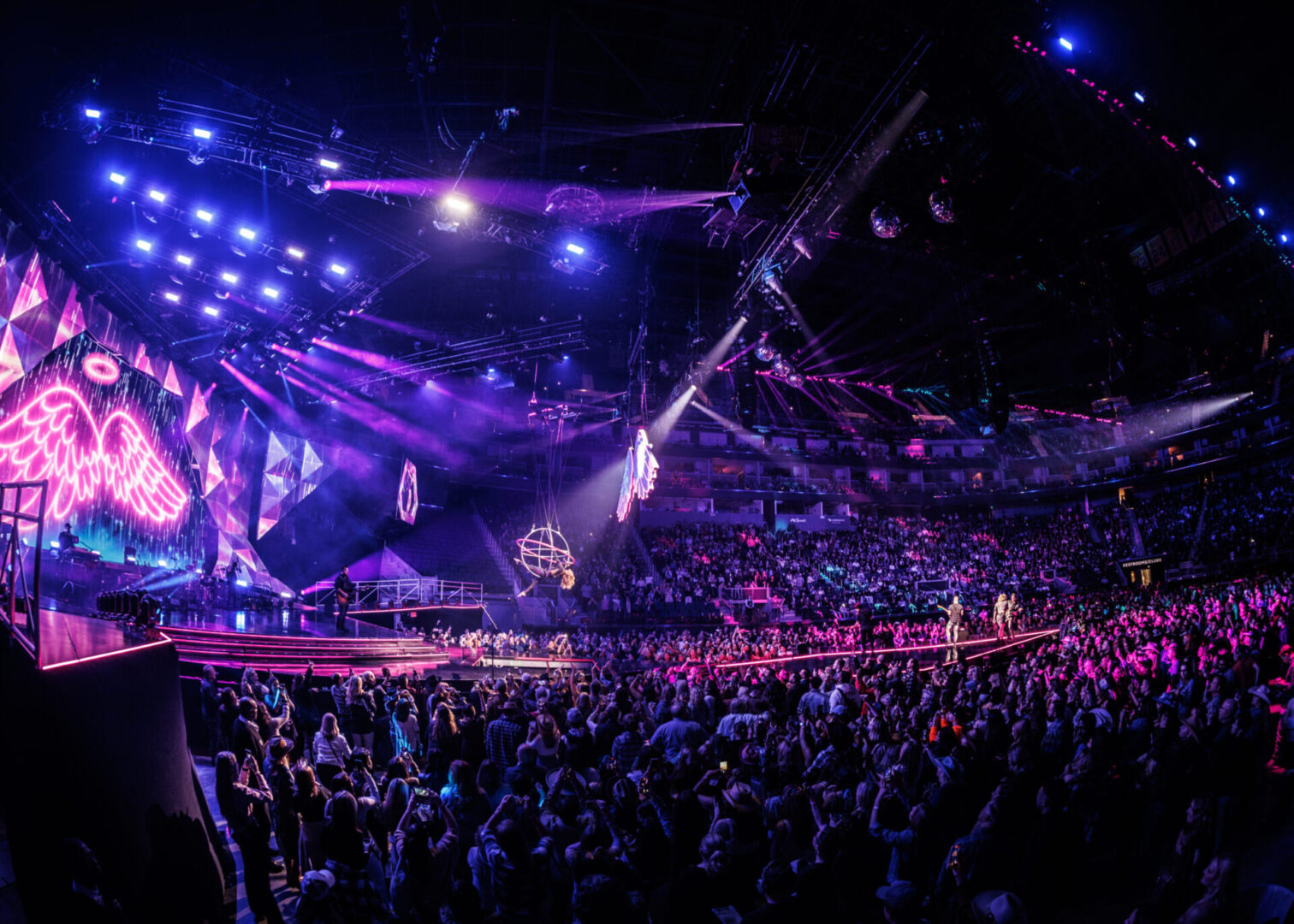 A lively concert with vibrant lights and a large cheering crowd.