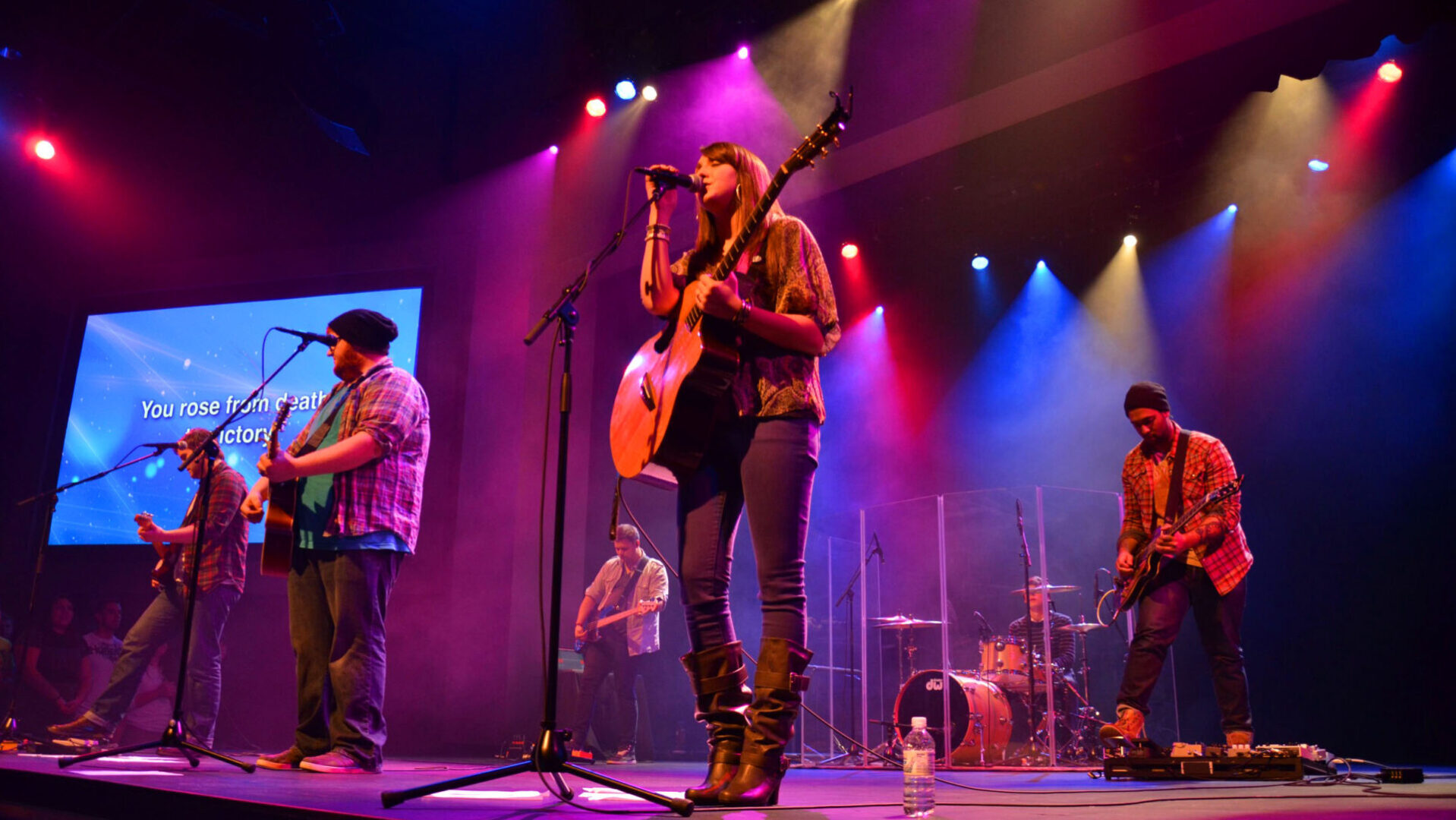 Band performing live on stage with vibrant lighting.