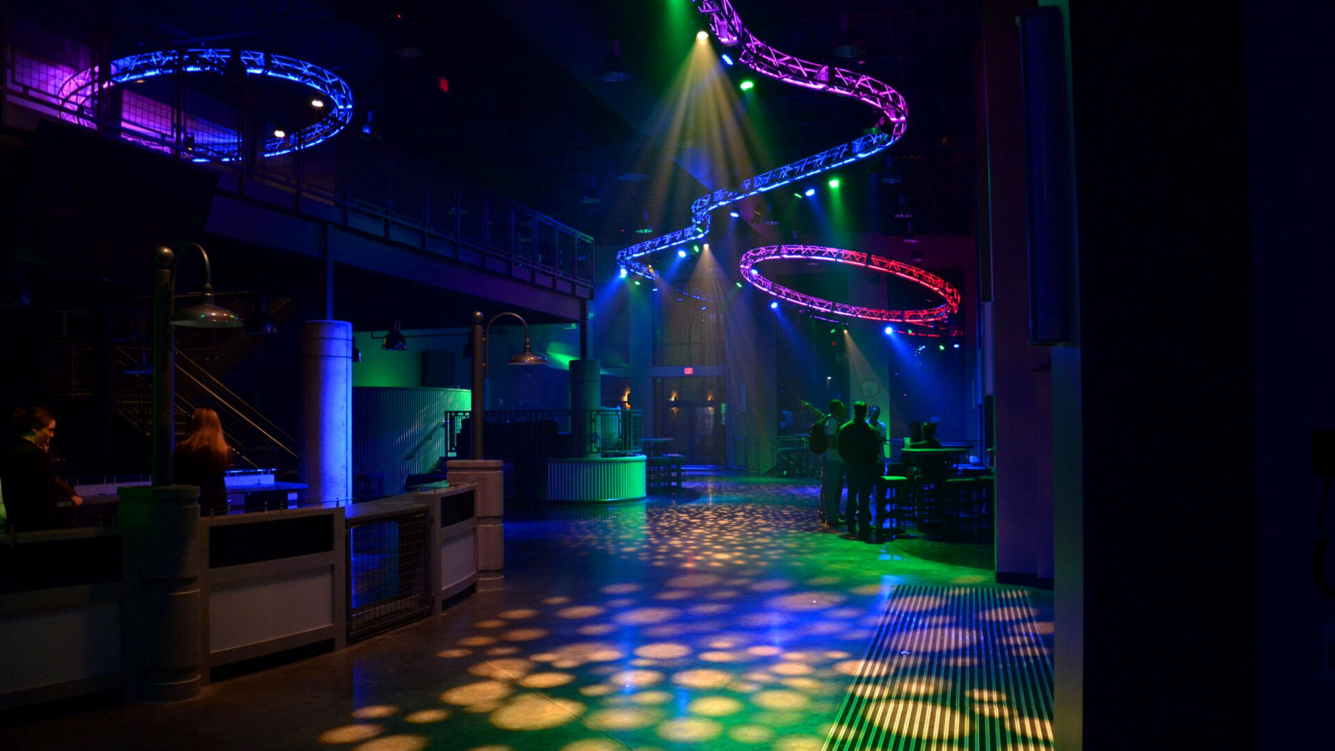 A vibrant nightclub with colorful lights and empty dance floor.