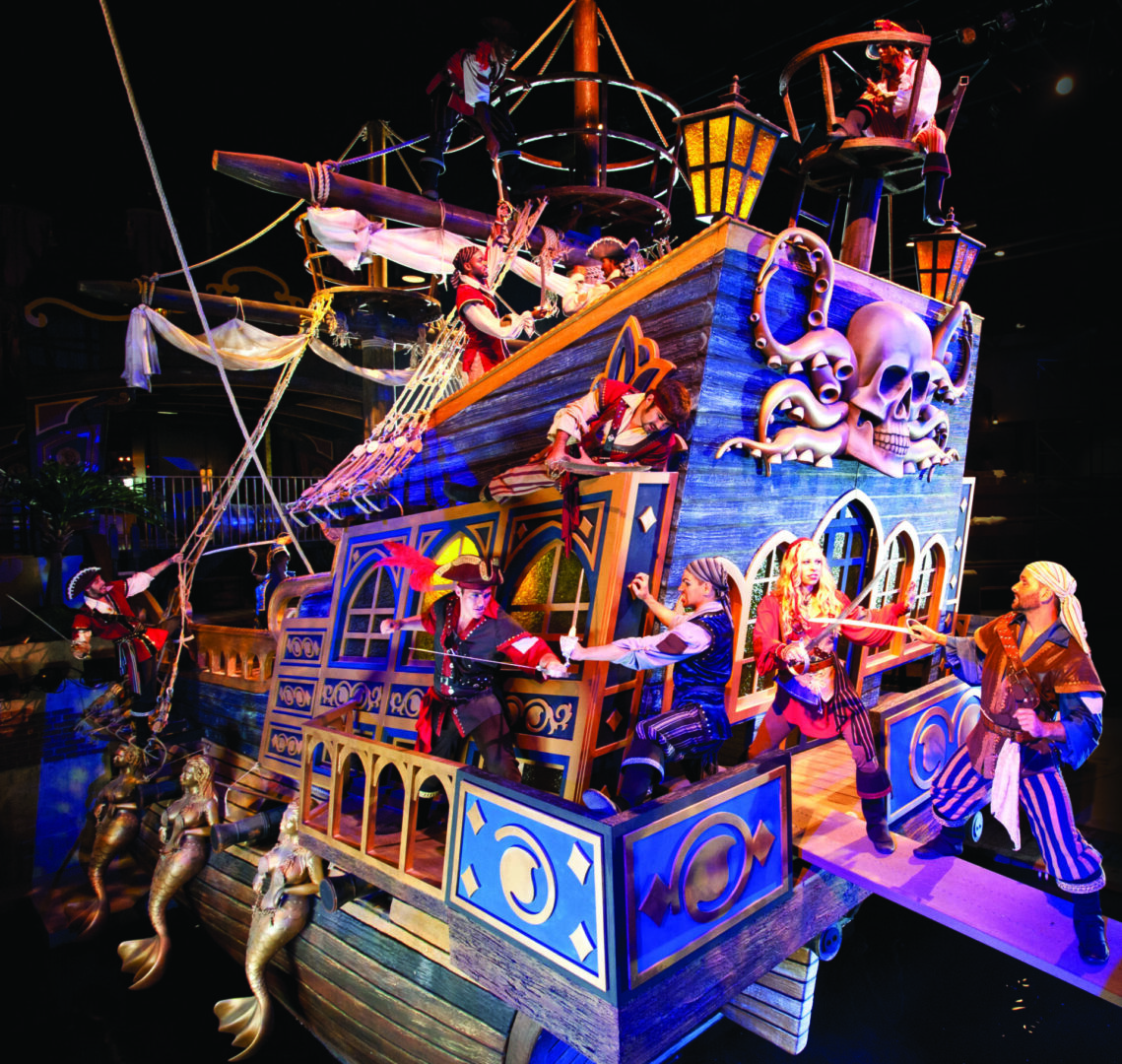 A vibrant pirate ship float with colorful lights and characters at night.