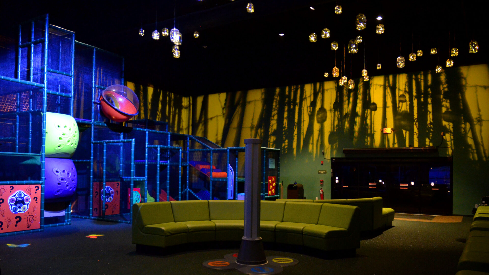 Dimly lit modern lounge with yellow sofas and hanging lights.