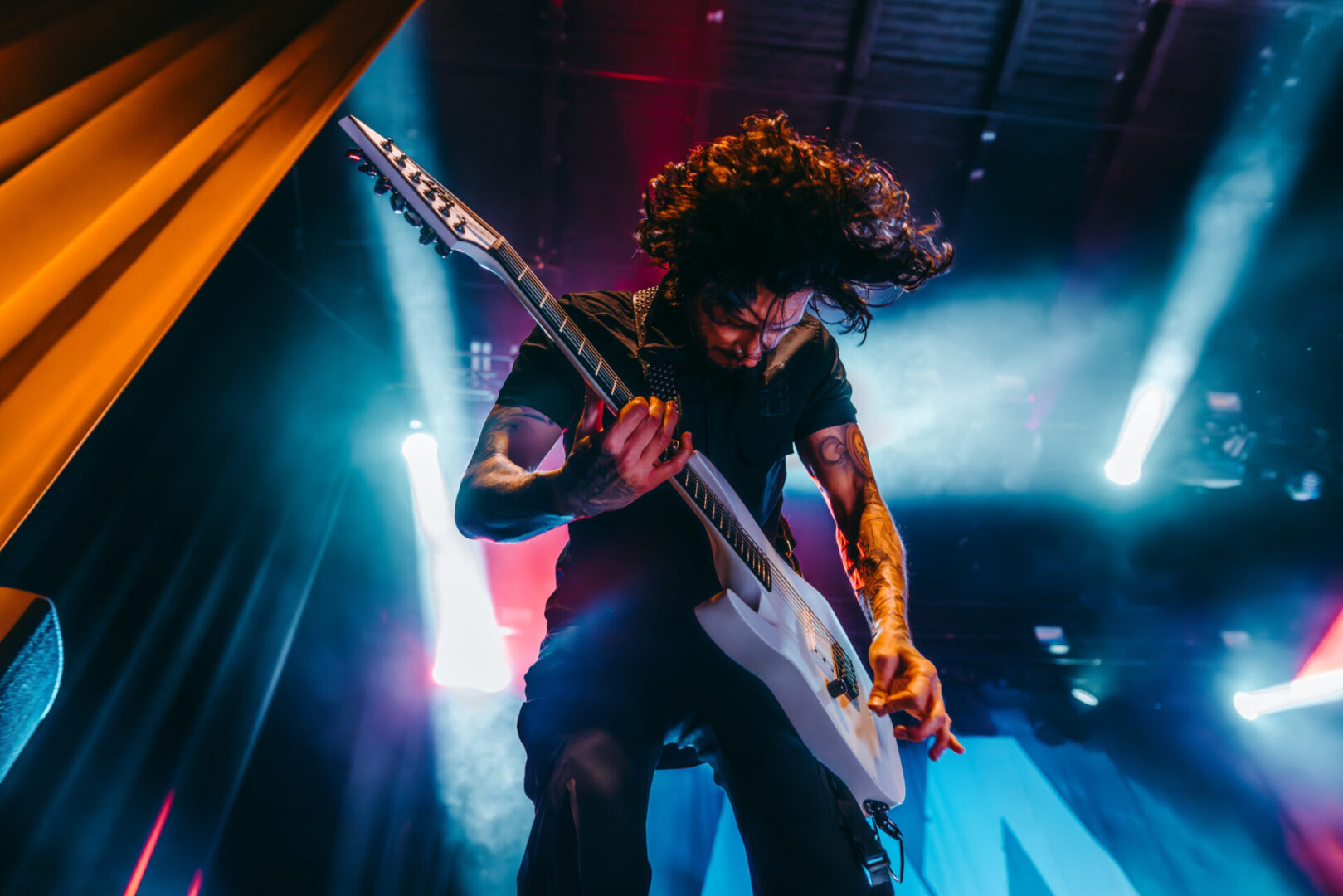 A man playing an electric guitar on stage during an Asking Alexandria tour.