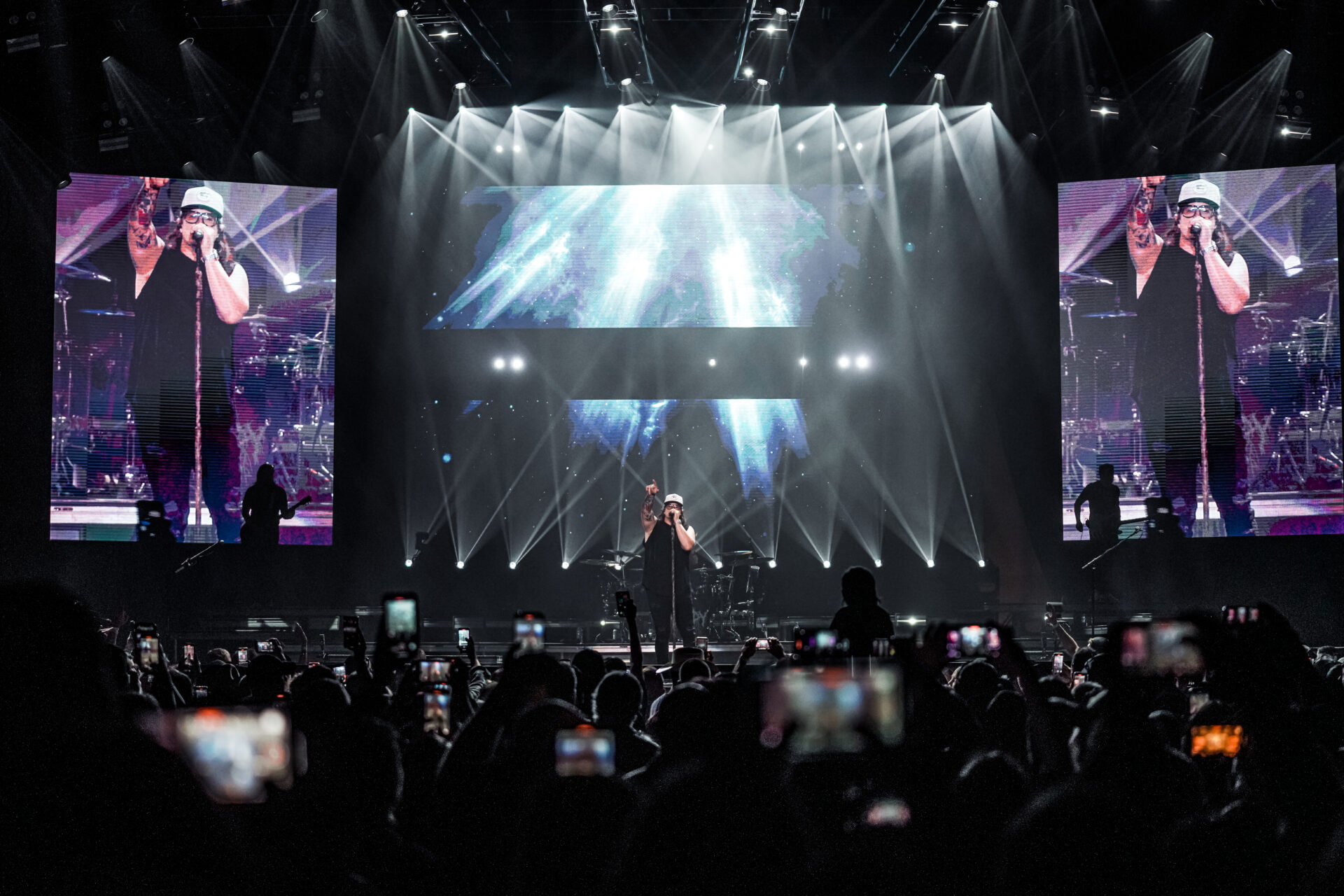 A performer on stage with dramatic lighting and a large crowd.