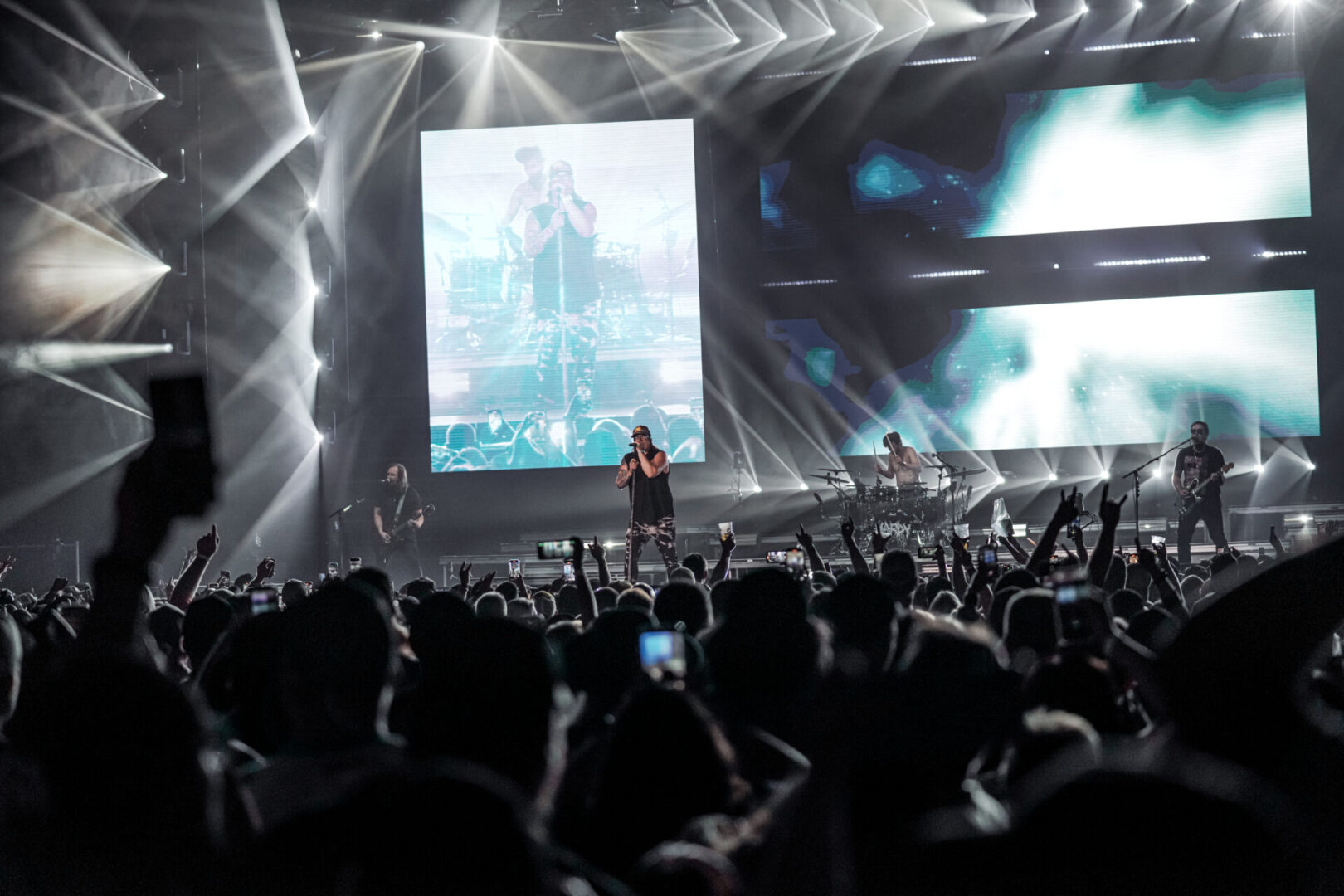 A singer performs on stage with a large screen and vibrant lights at a concert.
