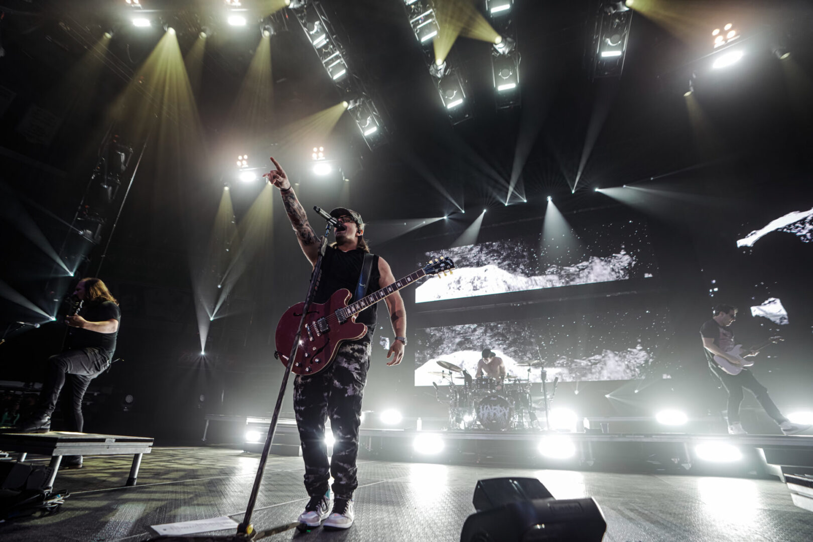 Guitarist performing energetically on stage with dramatic lighting.