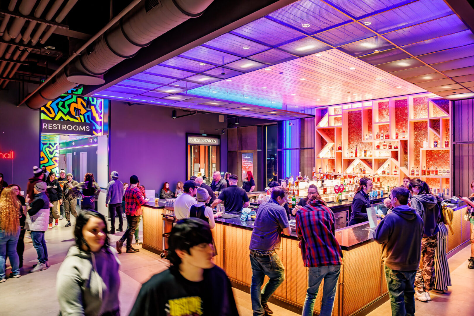 People socializing in a vibrant bar with colorful lighting.