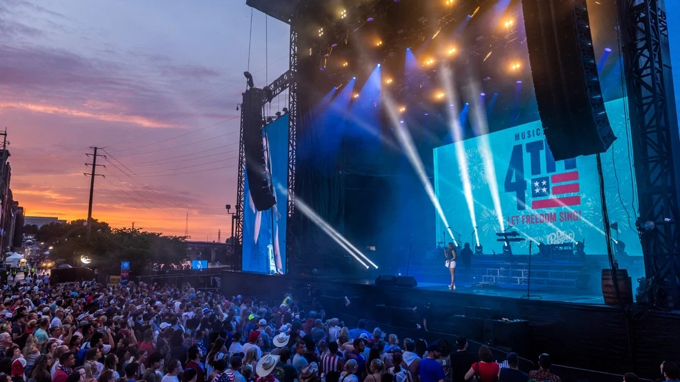 Crowd enjoying a sunset concert with vibrant stage lights.