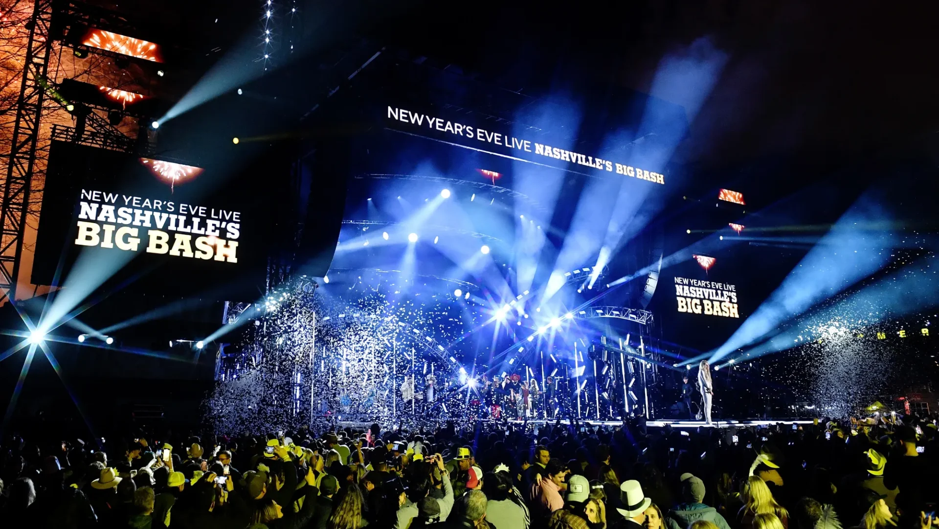 New Year's Eve celebration with lively crowd and dazzling stage lights.