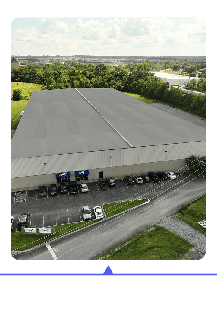 A large warehouse with trucks parked outside on a sunny day.