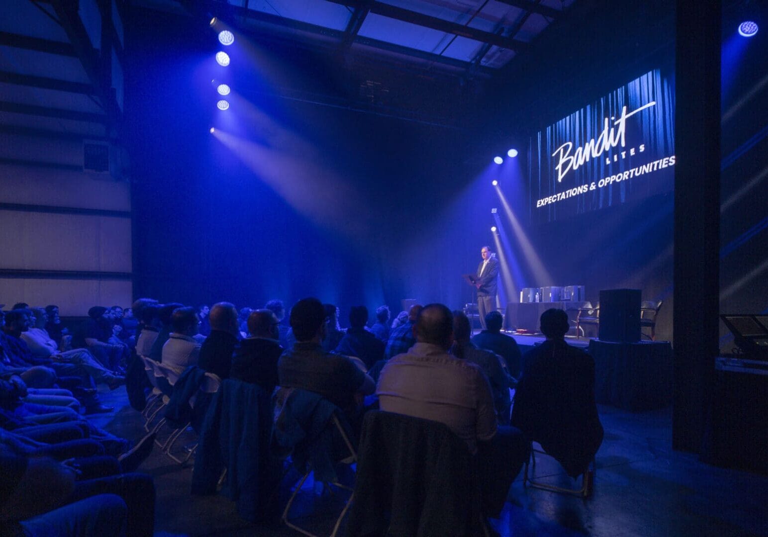 Crowd enjoying a live music performance under blue stage lights.