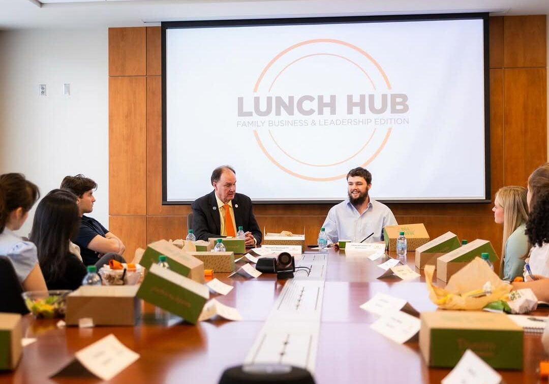 People gather around a table for a Lunch Hub meeting with meal boxes.