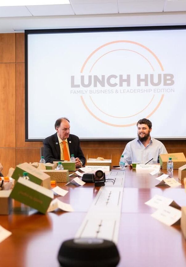 People gather around a table for a Lunch Hub meeting with meal boxes.