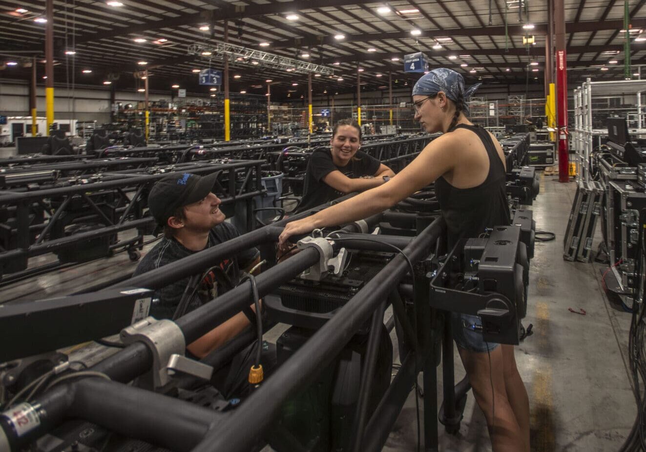 Workers collaborate on assembling large industrial pipes inside a factory.