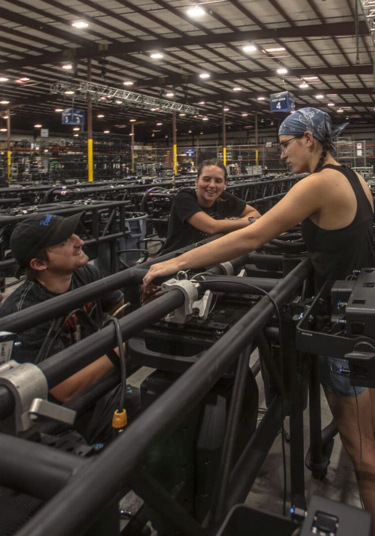 Workers collaborate on assembling large industrial pipes inside a factory.