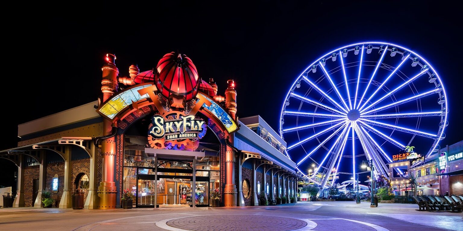 Night view of an amusement park entrance with a Ferris wheel.