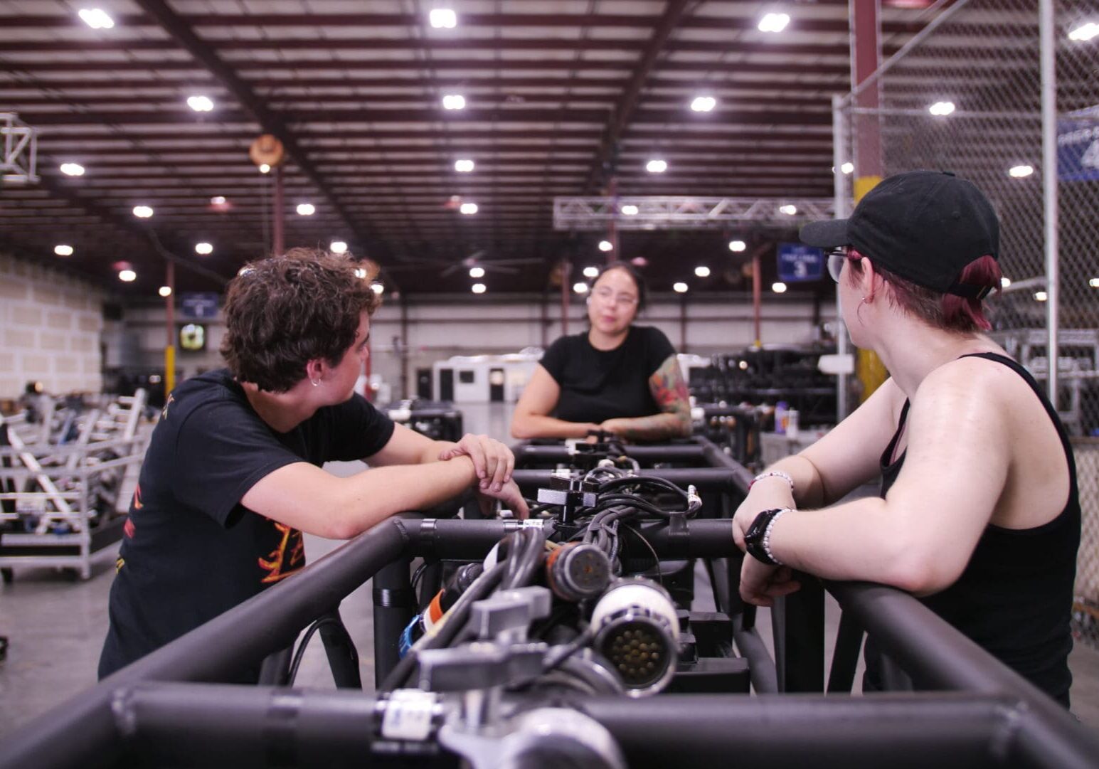 Three people working on a complex machine in a workshop.