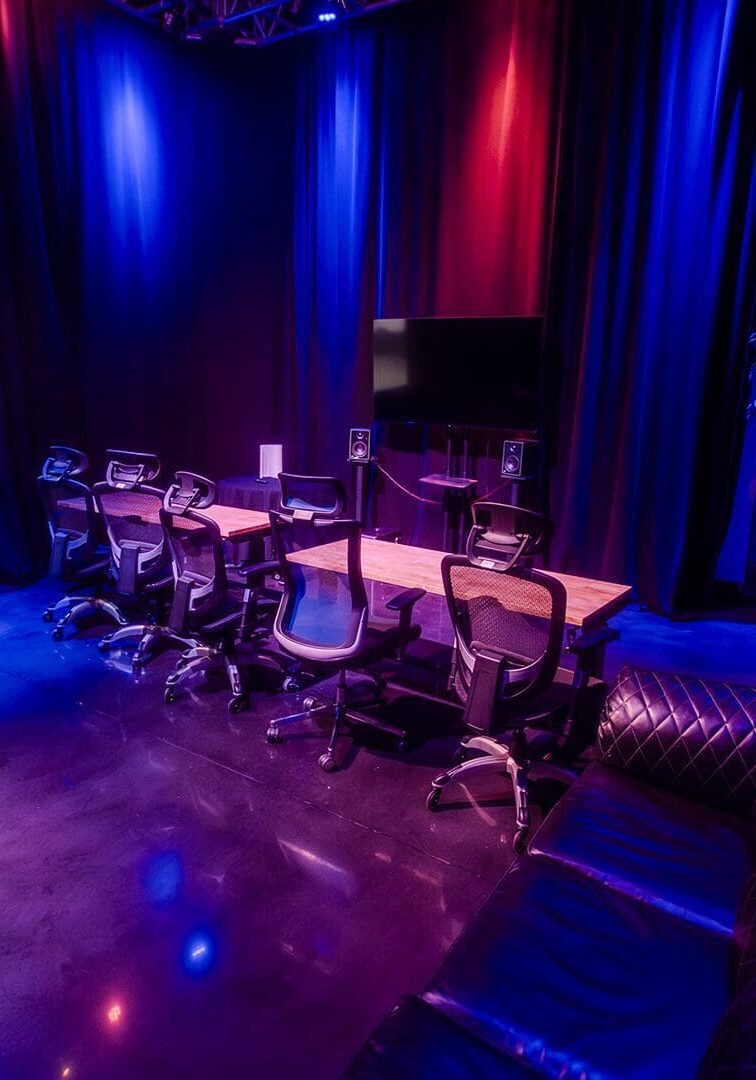 Dimly lit lounge with musical instruments and cozy seating under blue and purple lights.