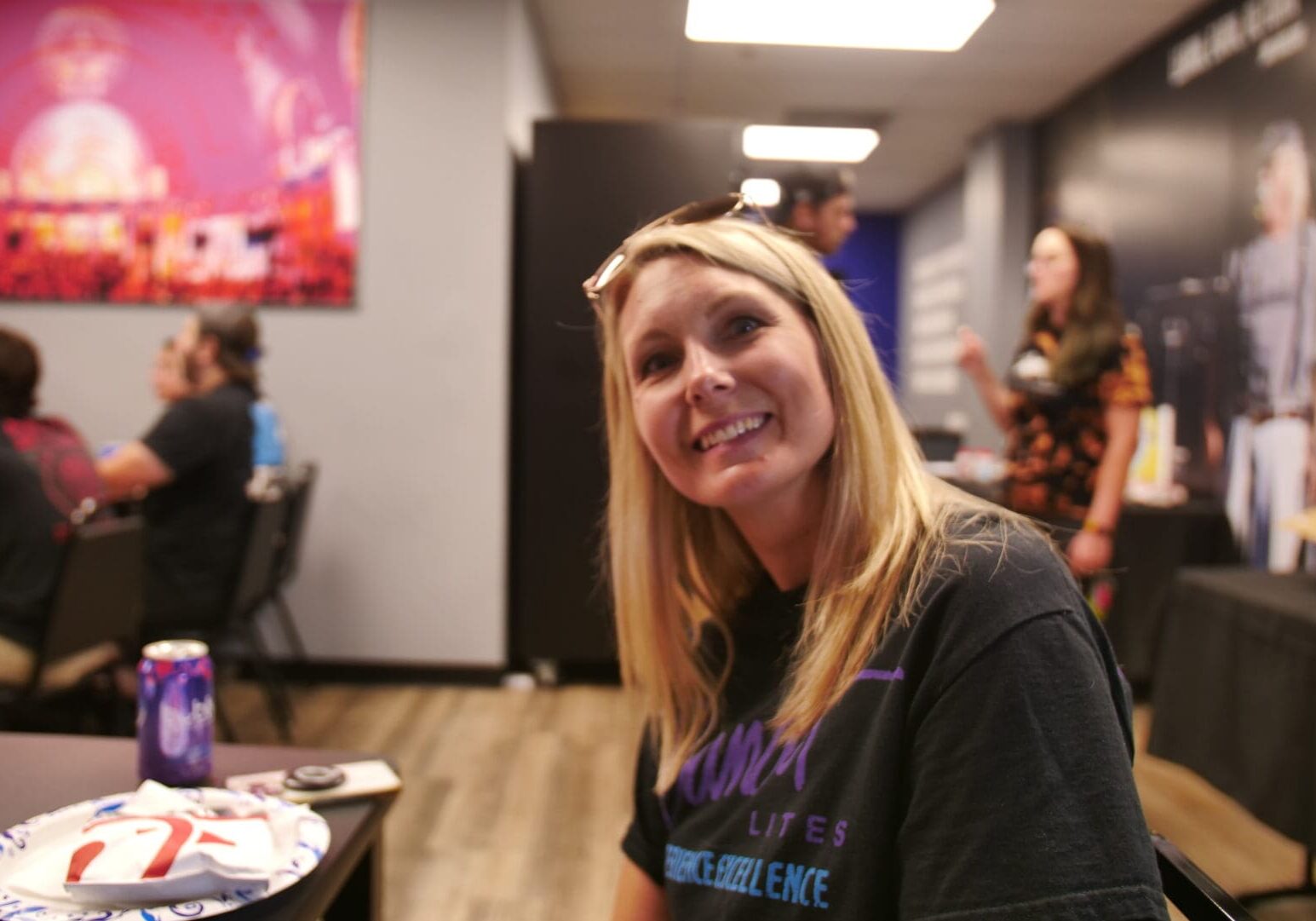 Smiling woman with sunglasses on her head in a casual indoor setting.