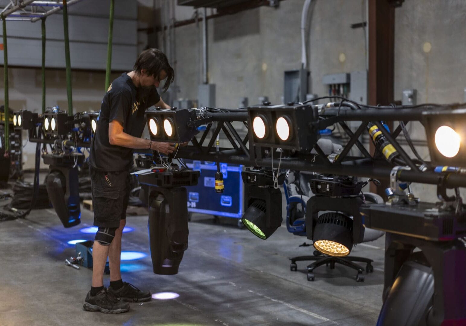Technician adjusting stage lighting equipment in a warehouse.