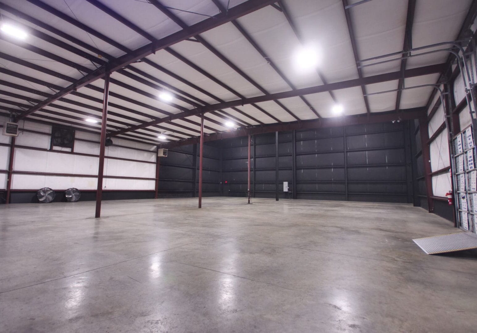 Empty industrial warehouse with polished concrete floor and metal beams.