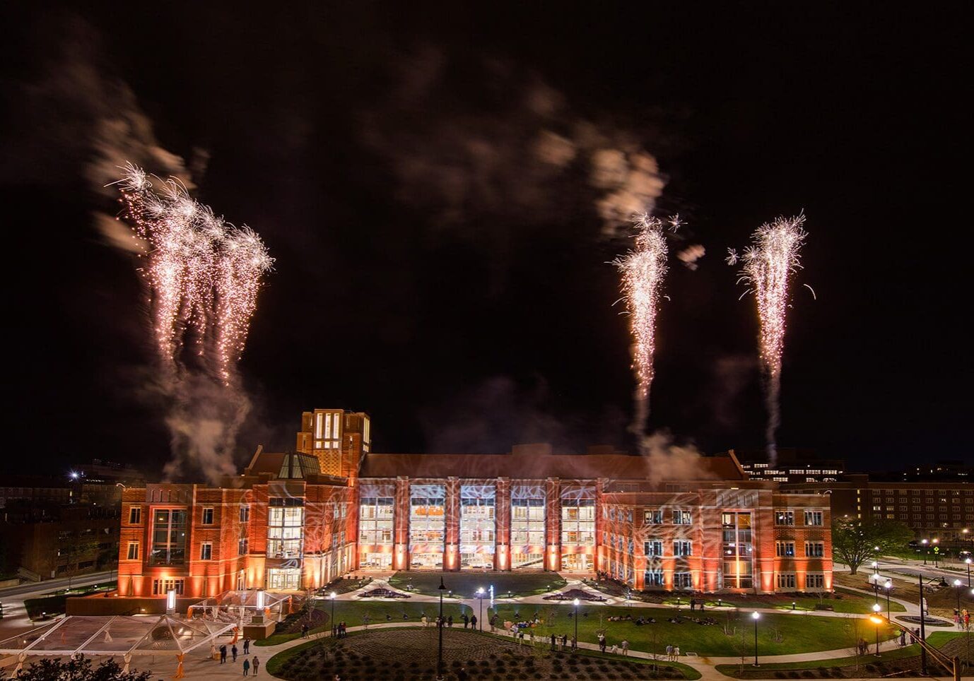 Fireworks illuminate a grand building against the night sky.