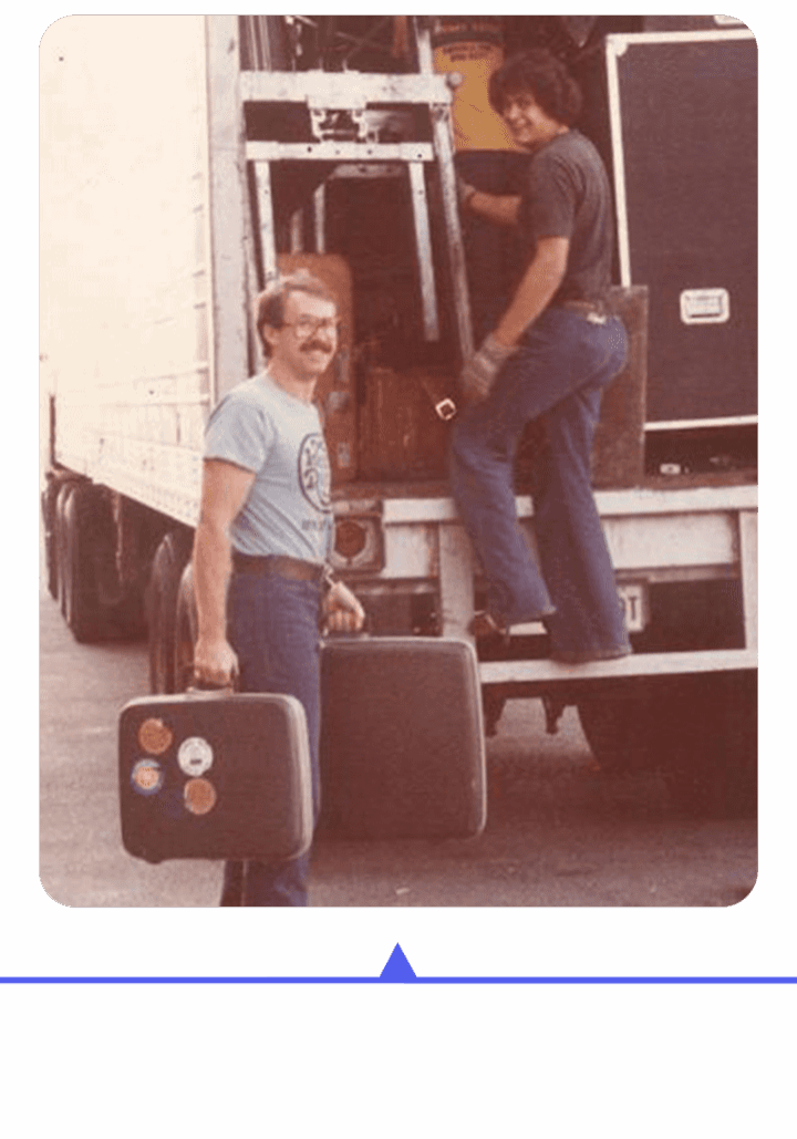 Two women with luggage, one climbing into a truck.