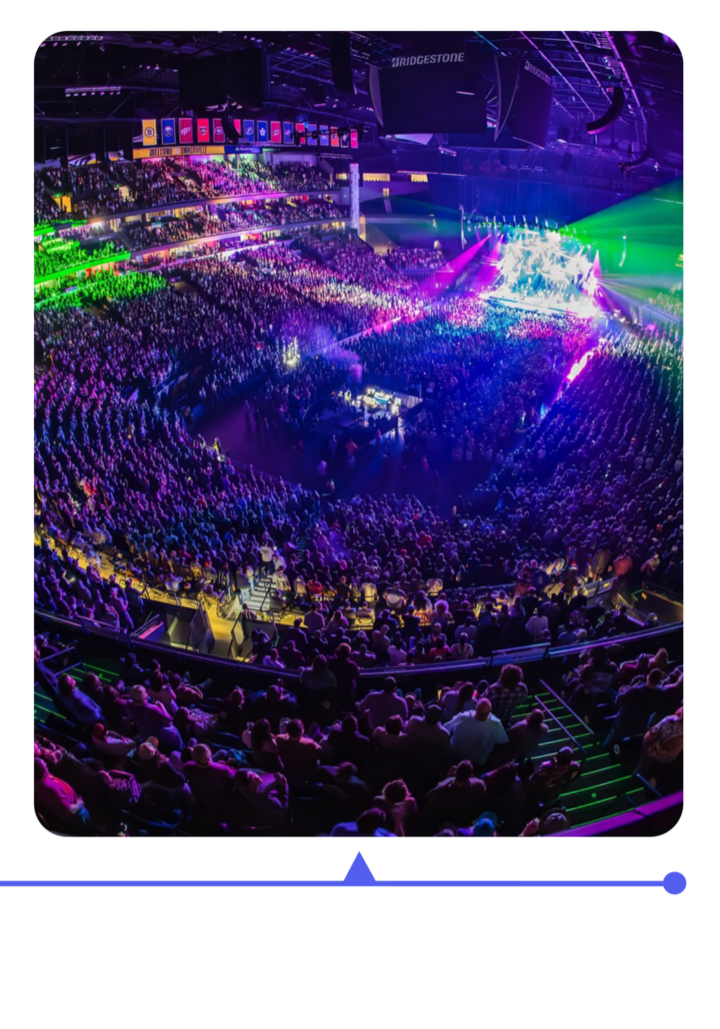 A packed arena lit with colorful lights during a concert.