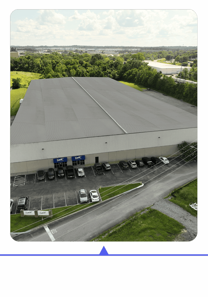 A large warehouse with trucks parked outside on a sunny day.